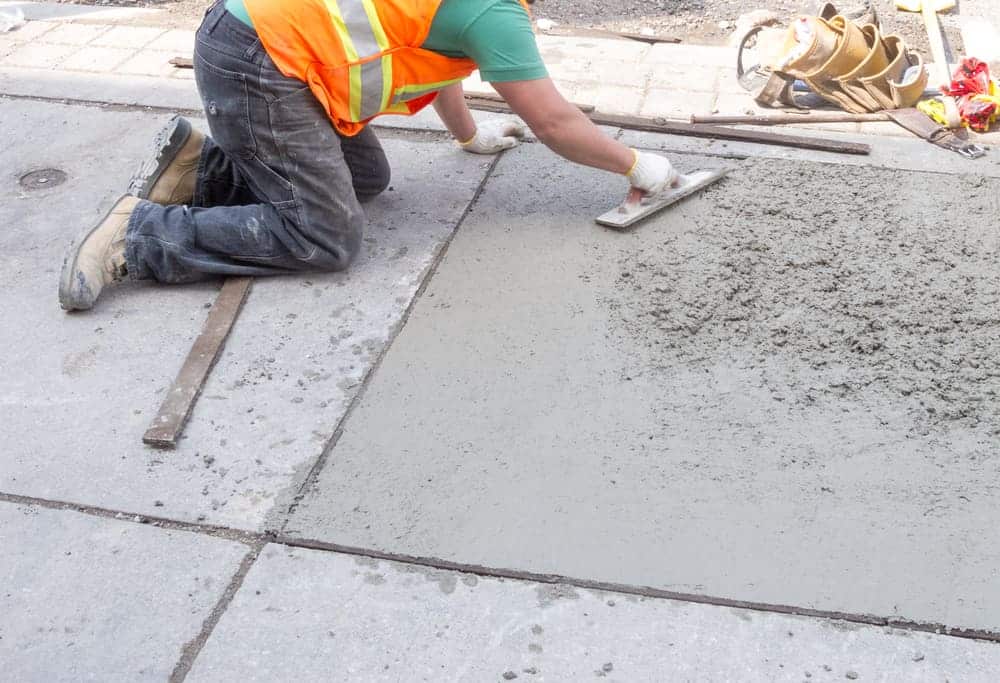 A mason resurfacing concrete pave with hand float